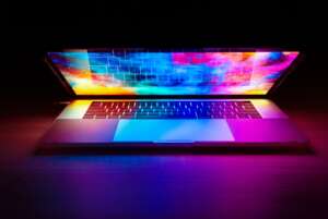 Macbook in the dark with a colorful picture on the screen and lid half open