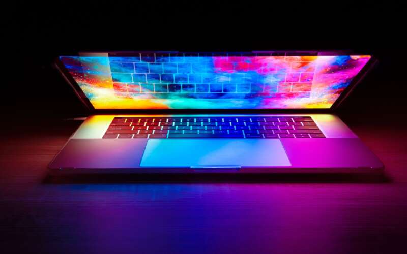 Macbook in the dark with a colorful picture on the screen and lid half open