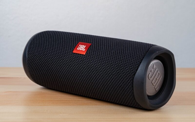 black JBL portable bluetooth speaker on brown wood table