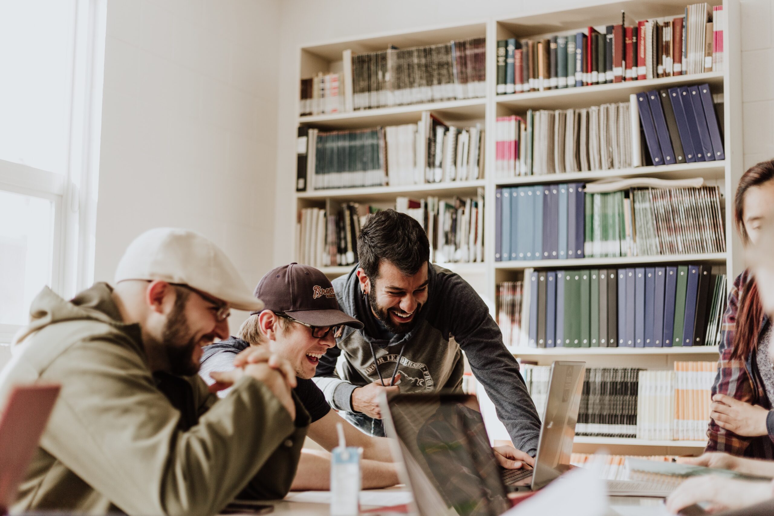 30 Best Gifts for College Guys in 2024 Three men laughing while looking at laptop in library