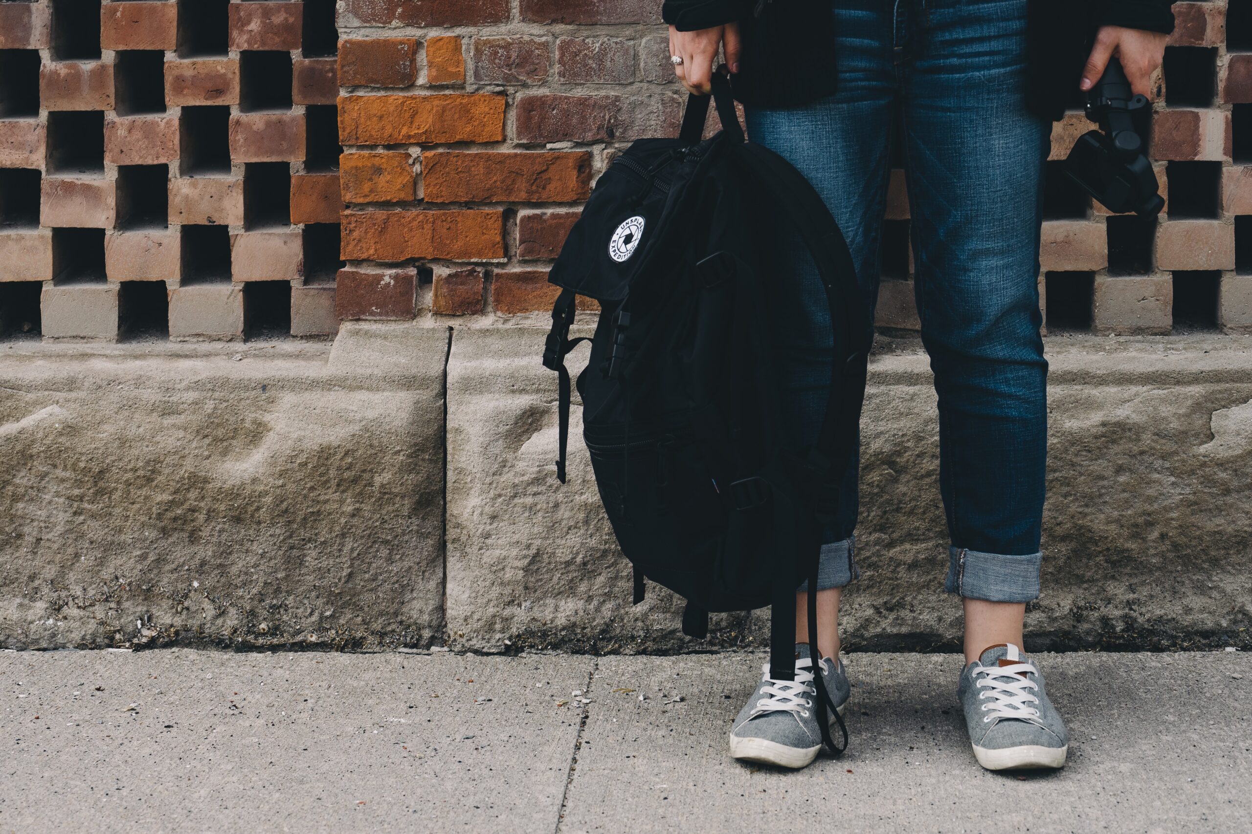 Top 10 Best College Backpacks for Students in 2021 Person standing on a sidewalk holding a black backpack