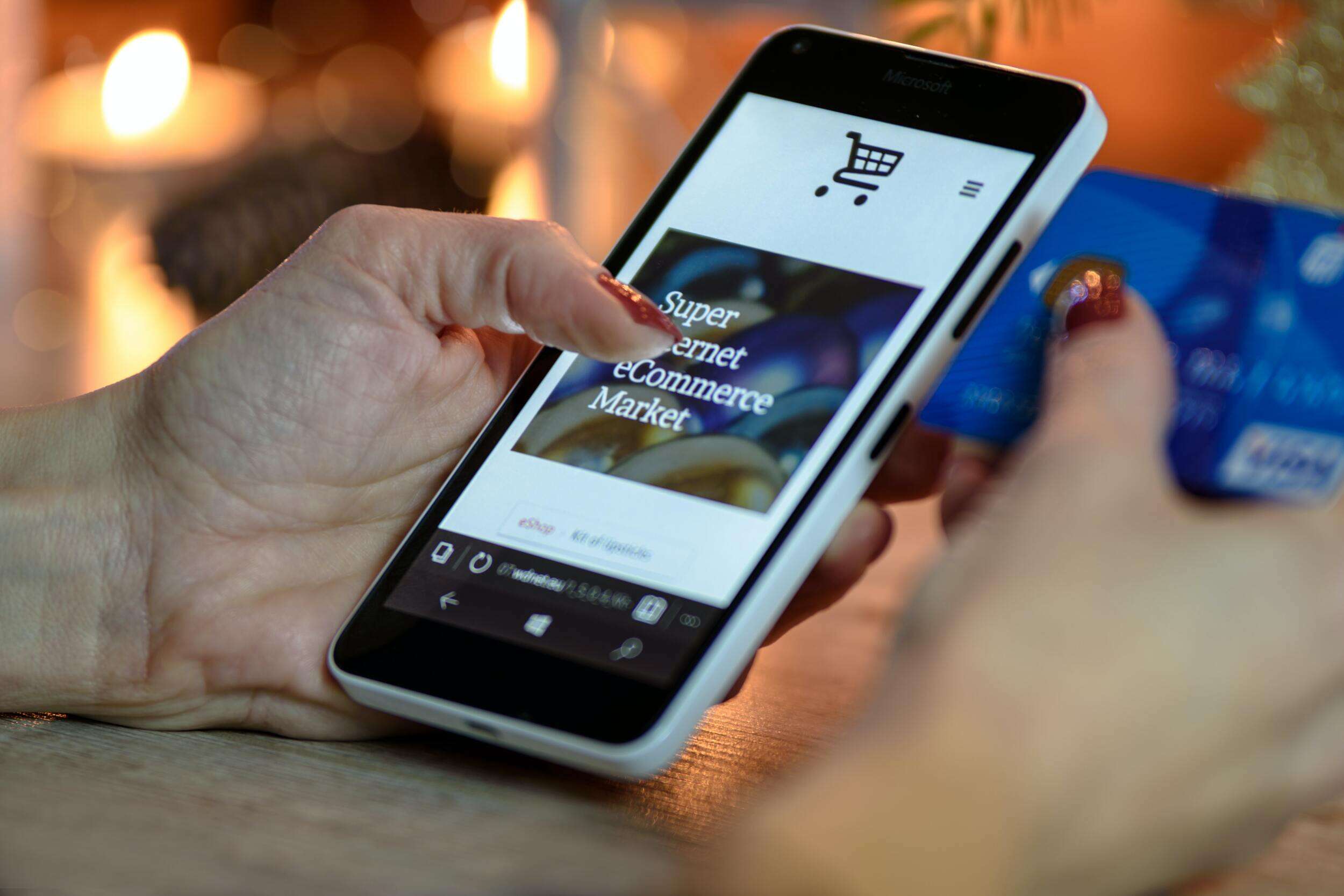 Person looking at a website on a smartphone and holding and blue card.