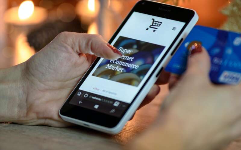 Person looking at a website on a smartphone and holding and blue card.