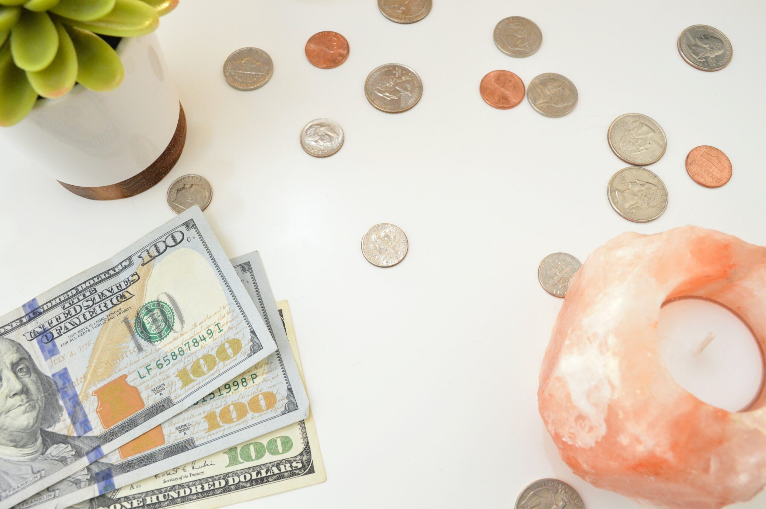 Three 100 dollar bills and change on a white table