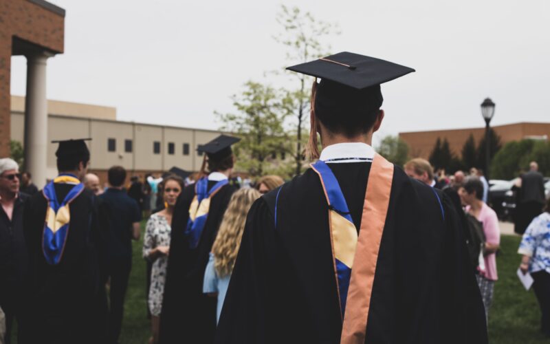 man wearing a black cap and gown outside on his graduation day