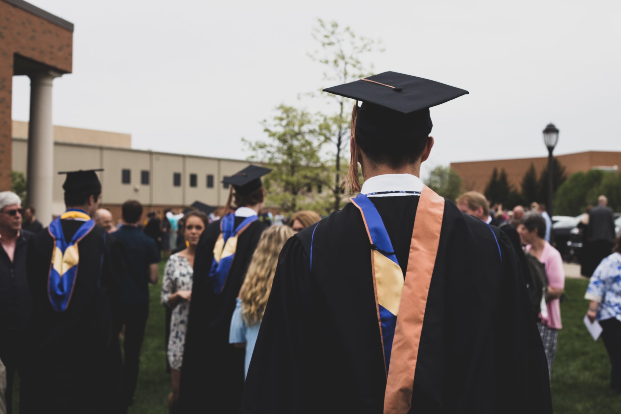 man wearing a black cap and gown outside on his graduation day