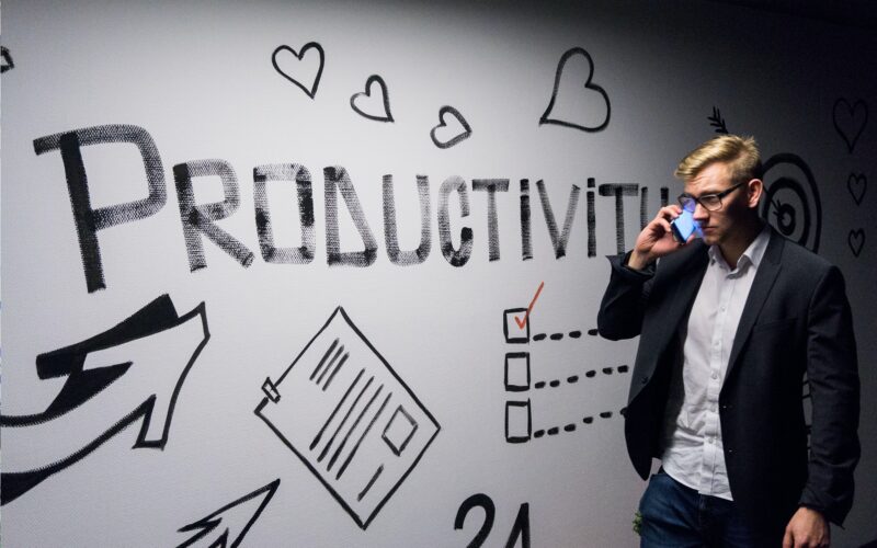 Man holding phone looking at productivity wall decor