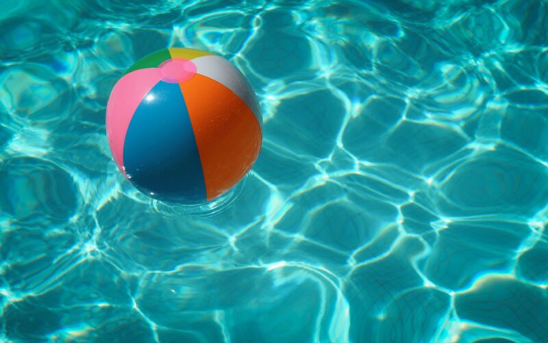 Multicolored beach ball in swimming pool during the day