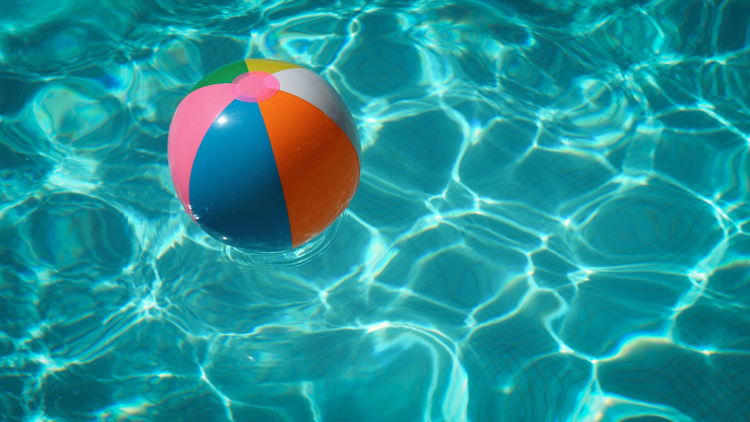 Multicolored beach ball in swimming pool during the day