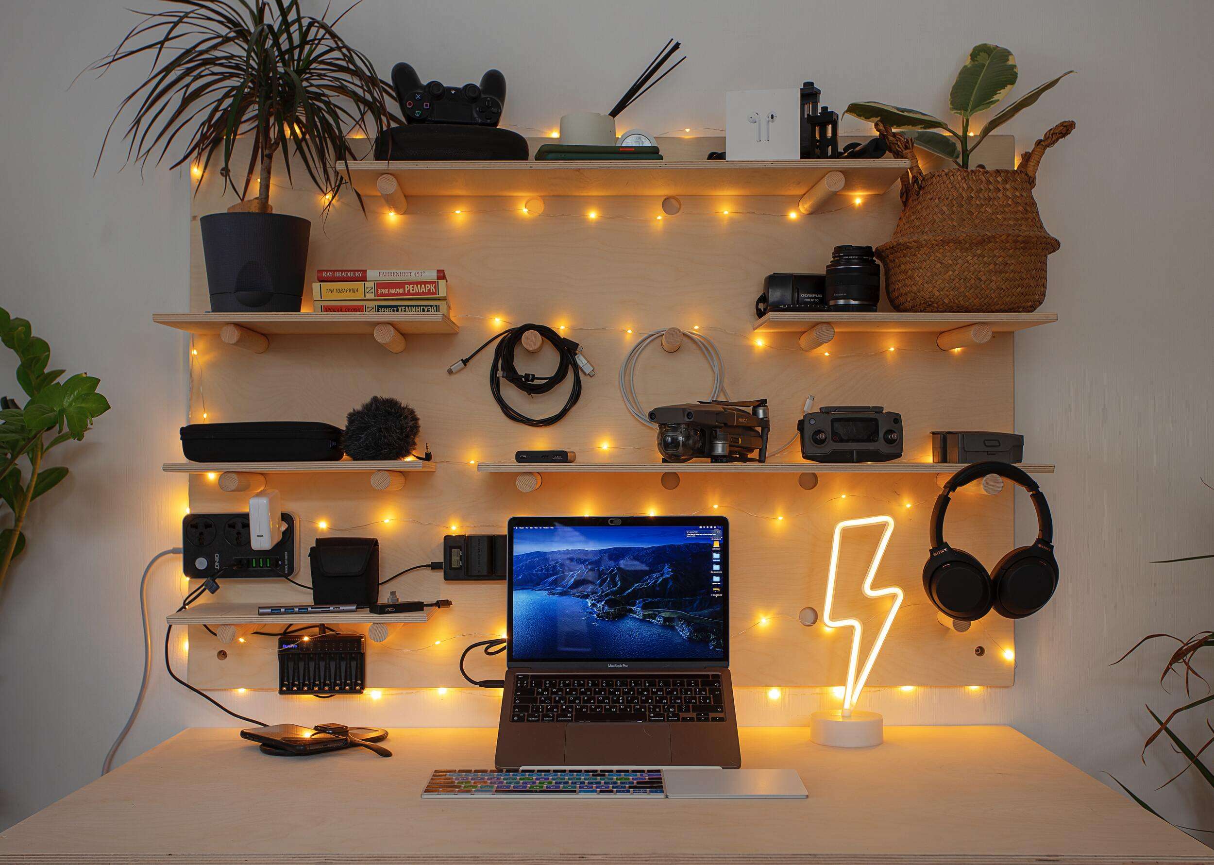 10 Dorm Organization Tips Students Need to Know laptop on desk with shelving and warm lights on the wall behind it