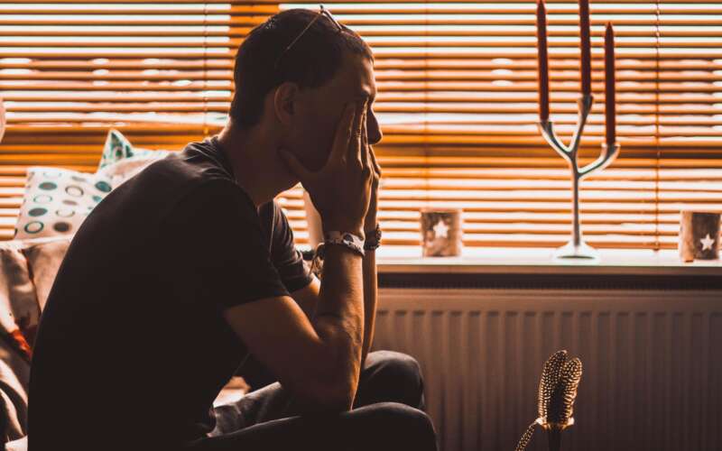 man in a room sitting in a chair covering his eyes