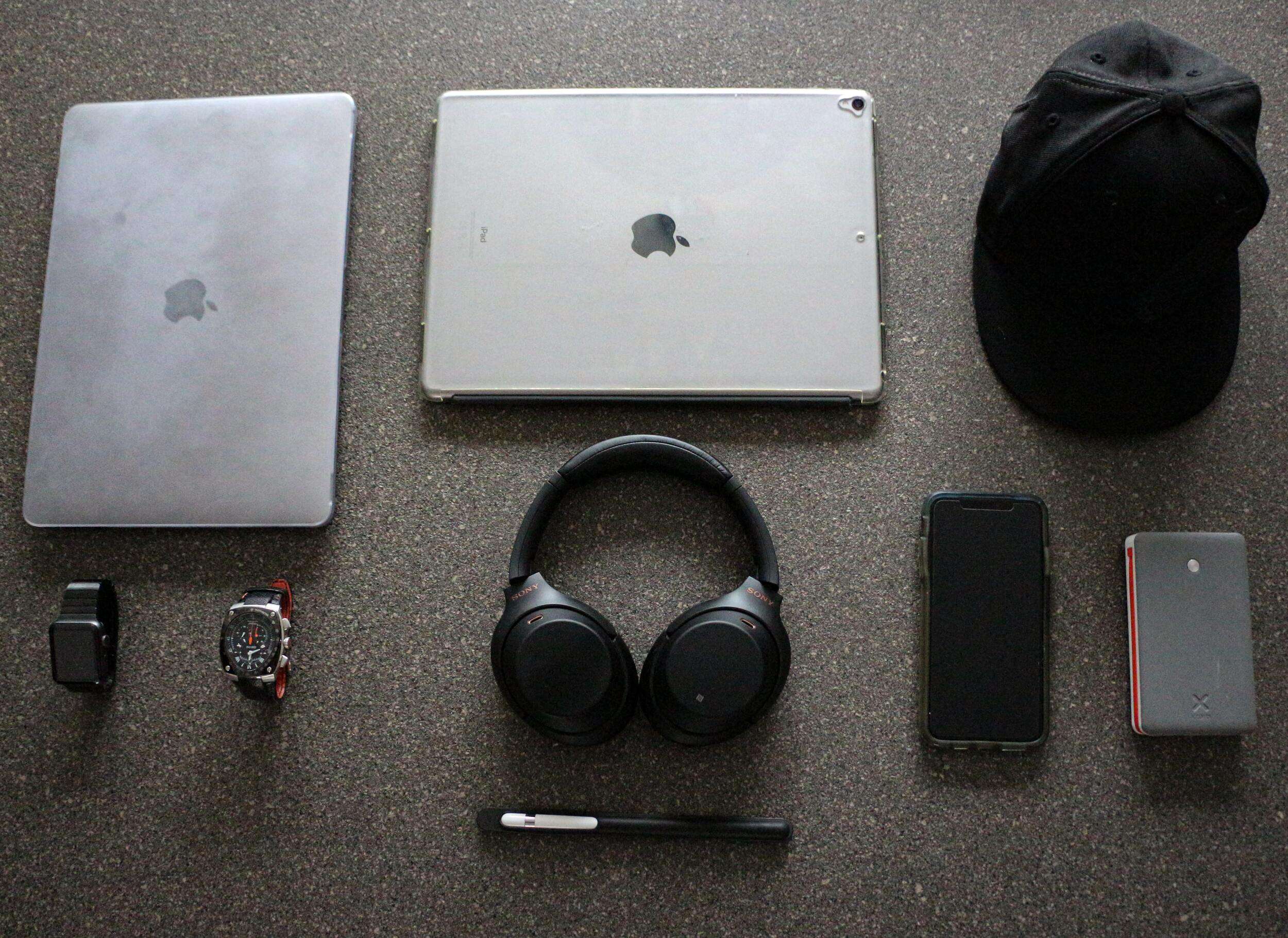 silver laptop beside silver tablet and black hat along with other edc gadgets