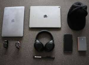 silver laptop beside silver tablet and black hat along with other edc gadgets