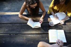 people sitting at table outside reading books