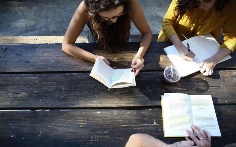 people sitting at table outside reading books
