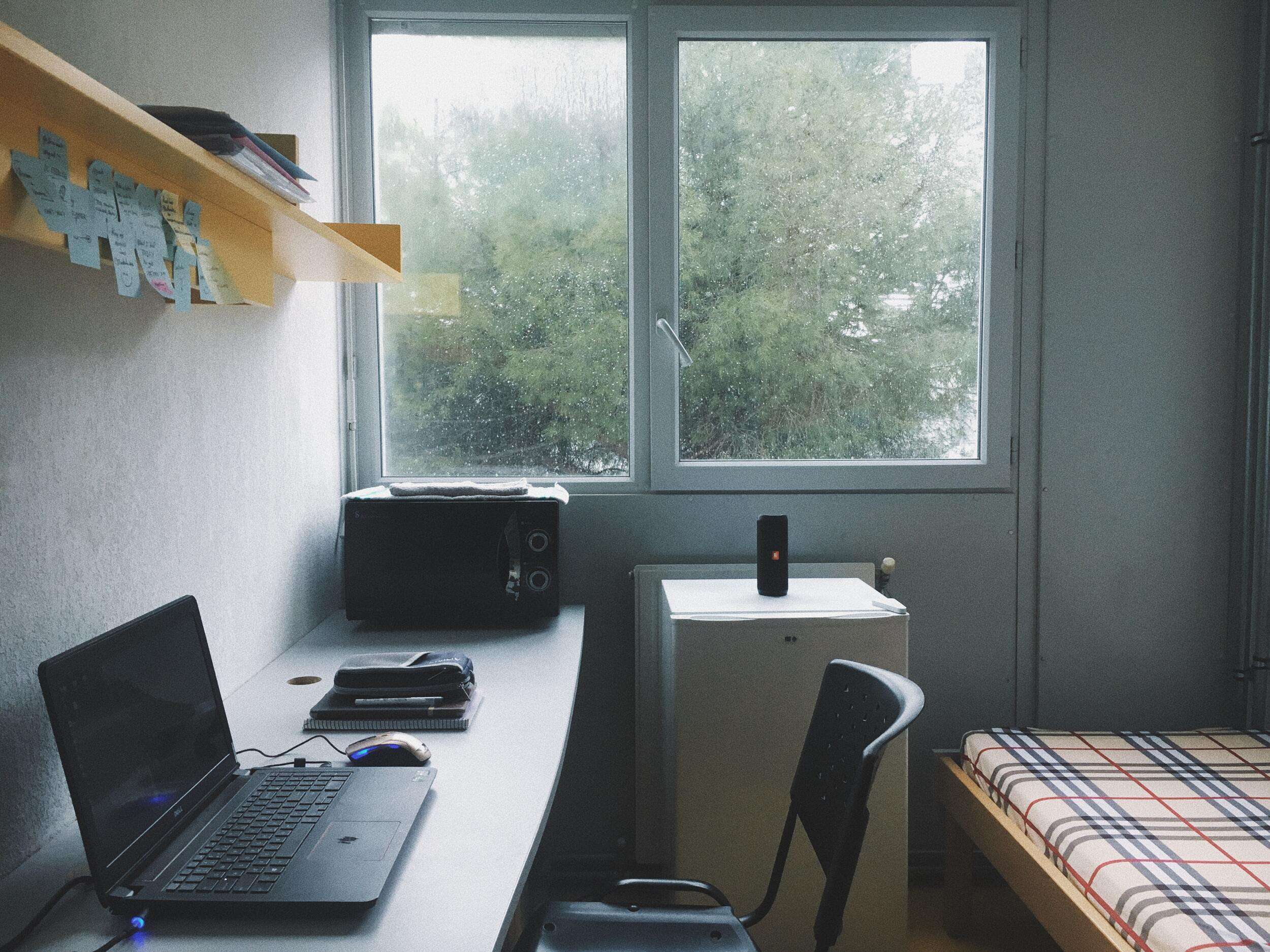 Dorm room with white walls and light coming in from the large window