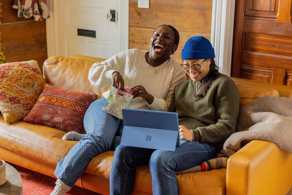 two women sitting on couch laughing