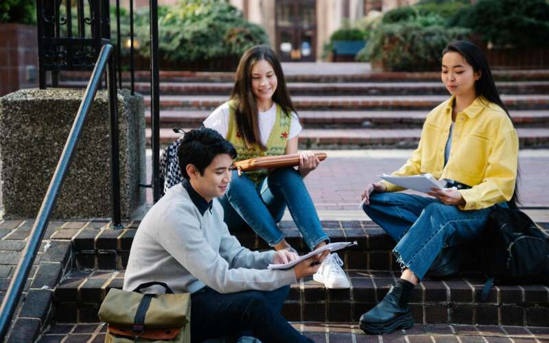 Three college students sitting outside on brick steps