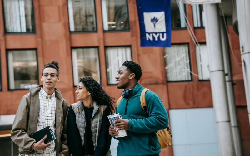 Three college students walking on NYU campus