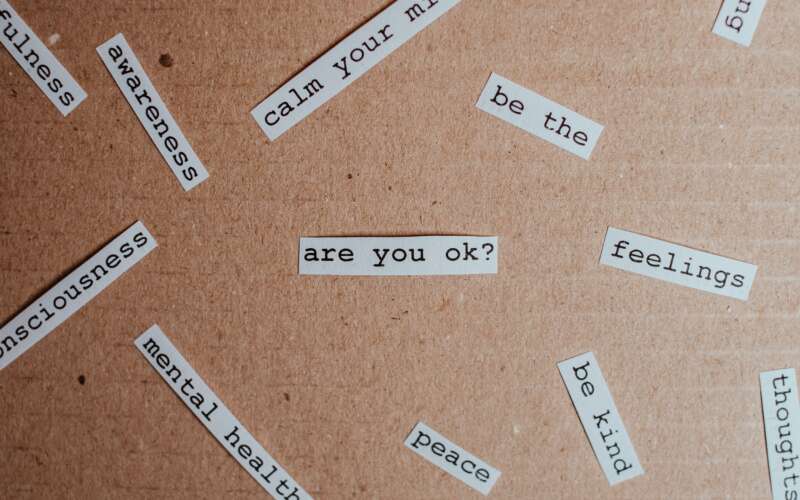 Small pieces of white paper with words and phrases related to mental health on them