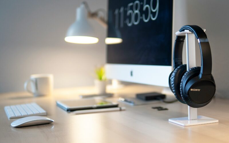 Black Sony headphones beside iMac on top of desk
