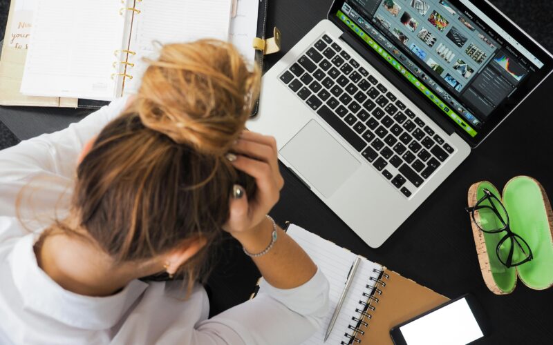 Women sitting down in front of her open laptop with a notebook to the side