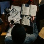 Above view of a man in a long sleeve shirt studying at a desk.