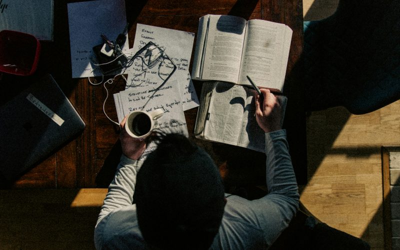 Above view of a man in a long sleeve shirt studying at a desk.