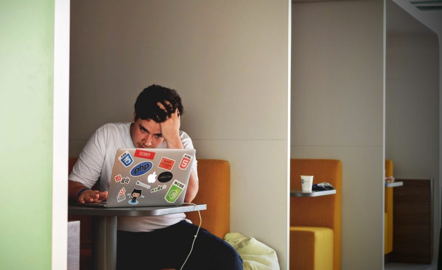 man sitting at a table using his MacBook for finals week